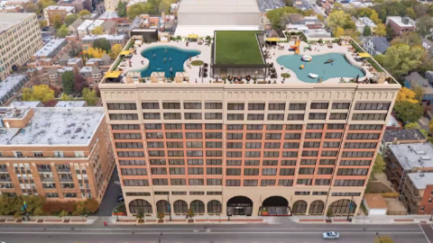An aerial rendering of an 14-story brick and stone building along a city street. 